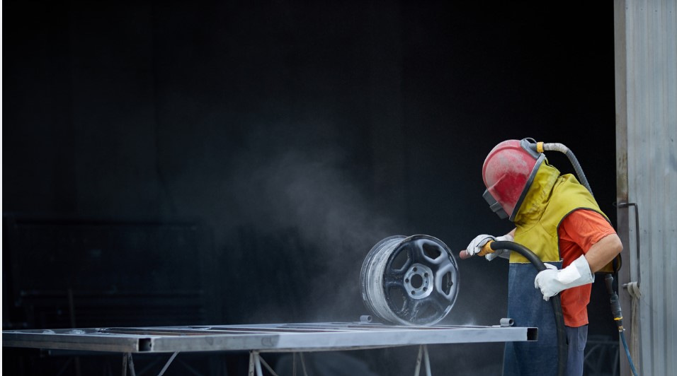 worker on safety wear while Sandblasting